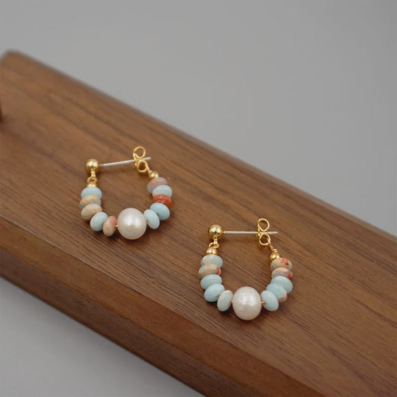 Fashion Jewellery Australia’s blue and white pearl hoop earrings showcased on a wooden stand, emphasizing their exquisite design.